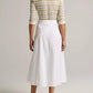 A person stands facing away, wearing a striped long-sleeve top, the Scarf Tie Skirt in white by vince, and light-colored sandals against a plain light background.
