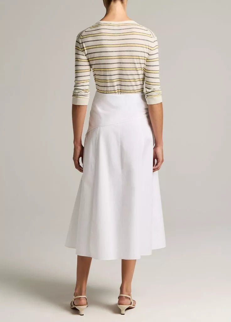 A person stands facing away, wearing a striped long-sleeve top, the Scarf Tie Skirt in white by vince, and light-colored sandals against a plain light background.