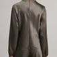 A person stands with their back to the camera, wearing the Vince Long Sleeve Draped Cowl Blouse paired with matching pants, set against a plain background.