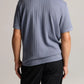 A person stands facing away, wearing the vince Drop Needle Stripe SS Polo in light purple and black pants against a neutral background.
