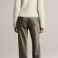 A person stands facing away against a plain background, wearing a fuzzy light-colored sweater paired with the Vince Colette High Waisted Fluid Satin Bias Pant in a silky gray shade.