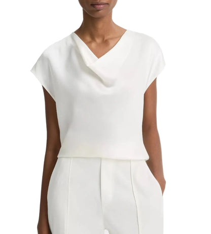 A woman is shown from the waist up wearing the Vince Cowl Neck Cap Sleeve Silk Blouse in off-white, styled with matching high-waisted pants and her hands in her pockets.