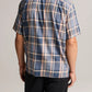 A person is seen from the back wearing the vince Prine Plaid Short Sleeve Cabana shirt in blue, beige, and pink cotton-blend twill with black pants, set against a plain background.