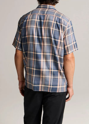 A person is seen from the back wearing the vince Prine Plaid Short Sleeve Cabana shirt in blue, beige, and pink cotton-blend twill with black pants, set against a plain background.