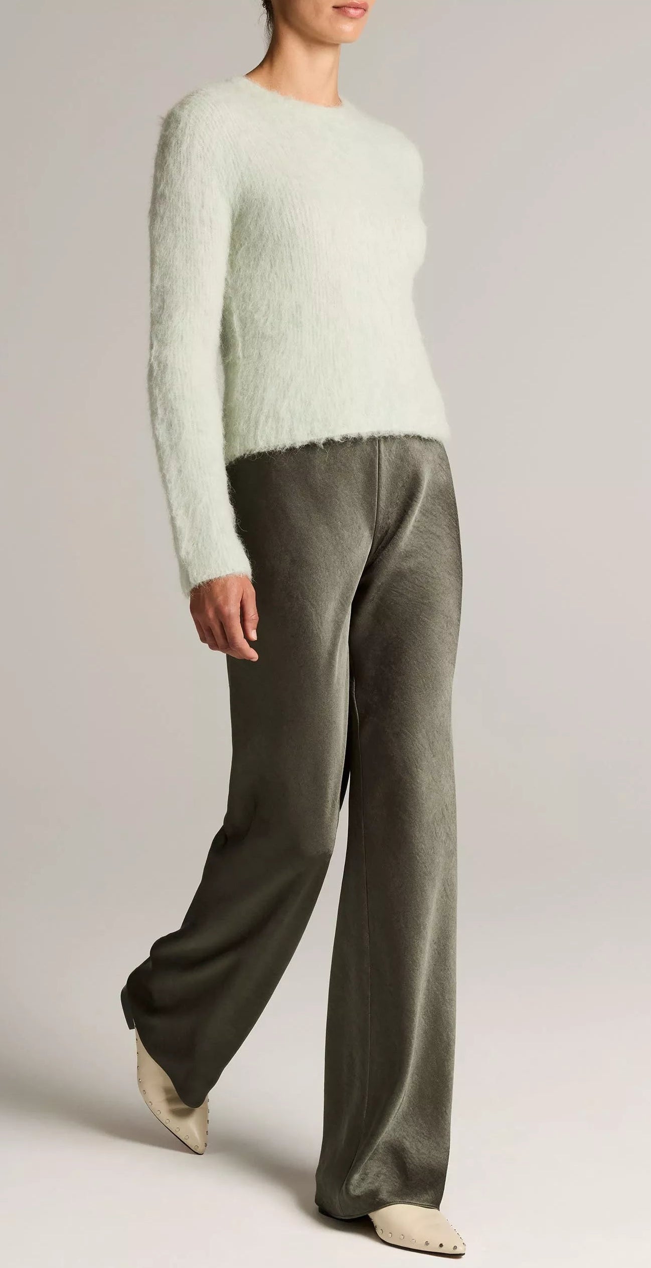 A person wearing a fuzzy light sweater, the Vince Colette High Waisted Fluid Satin Bias Pant, and cream pointed shoes stands against a plain background.