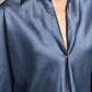 Close-up of a person wearing the Vince Bias Long Sleeve Blouse in a shiny, dark blue silk with a collar. Only the upper torso and part of the neck are visible, highlighting the elegant sheen of this summer blouse.