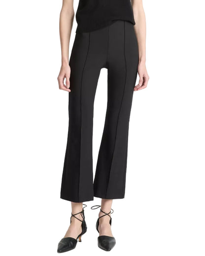 A person is shown from the shoulders down against a white background, wearing black Niki Mid Rise Crop Flare Pants by vince, crafted from luxurious Italian cotton-blend bi-stretch fabric, paired with black pointed-toe lace-up shoes.