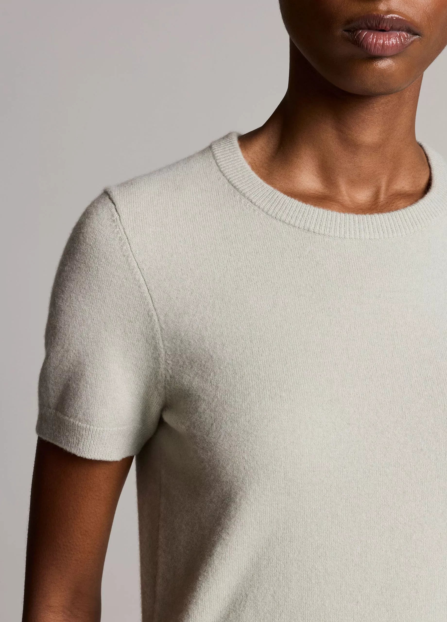 A person wearing the Vince Relaxed Short Sleeve Crew Sweater in light beige, shown from the shoulders to mid-torso against a neutral background.