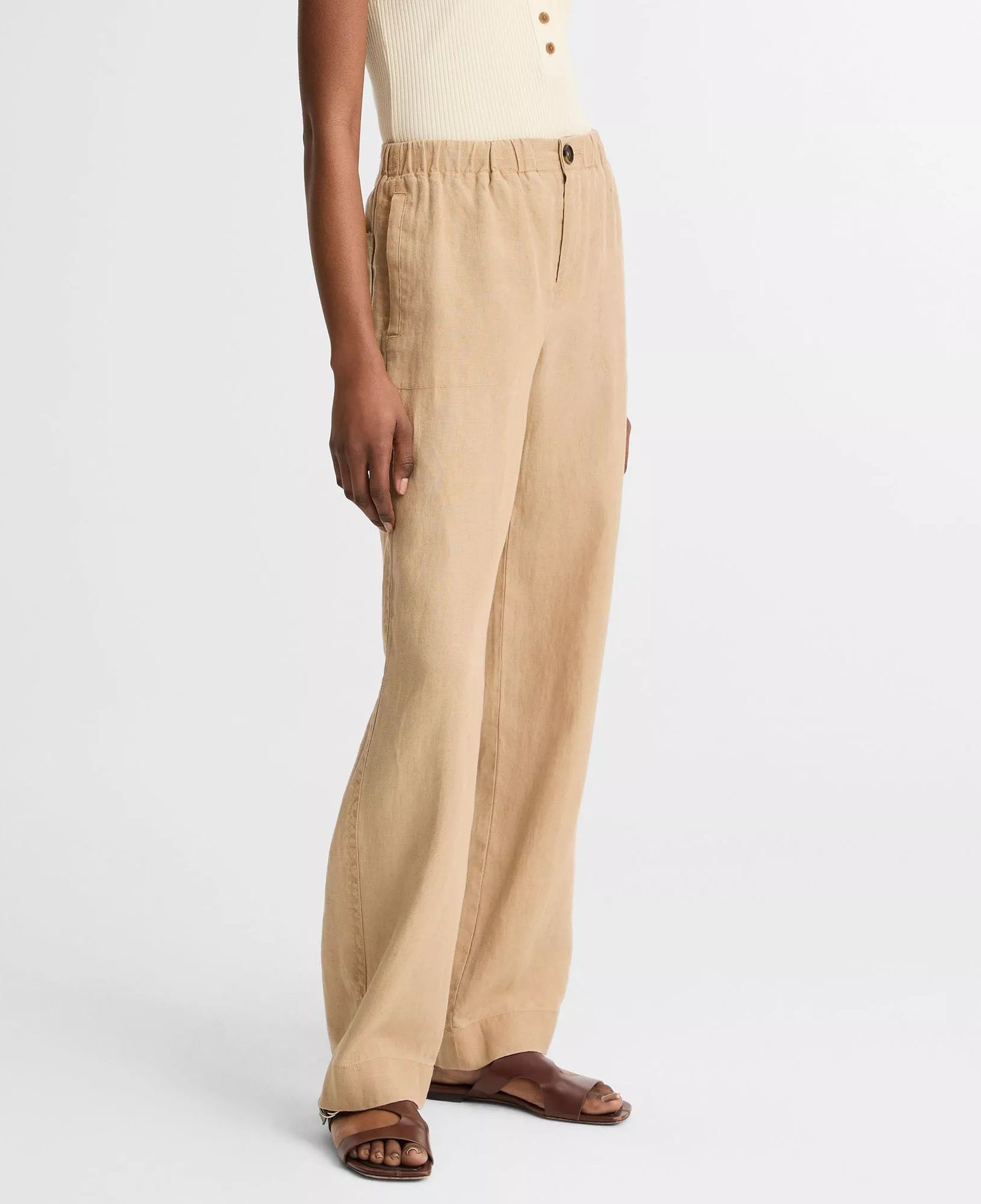 A person wears the vince Hemp Utility Pant with a sleeveless cream ribbed top and brown flat sandals, standing against a white background for a relaxed silhouette.