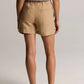 A person is standing facing away against a plain background, wearing vince’s Mid Rise Hemp Short in beige, featuring back pockets and a relaxed silhouette, styled with a white sleeveless top and brown sandals.
