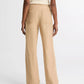 A person wearing vince’s Hemp Utility Pant in beige, featuring a relaxed silhouette, paired with a sleeveless ribbed top, is shown from the back against a plain white background.