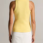 A person stands with their back to the camera, wearing the vince Ribbed Scoop Neck Tank in yellow—a finely ribbed, sleeveless cotton-modal blend top—paired with a white skirt featuring a yellow stripe, set against a plain background.