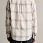A person is seen from the back, standing against a neutral background and wearing the Vince Townes Plaid Long Sleeve Shirt in a cream and light blue shadow plaid, paired with dark pants.