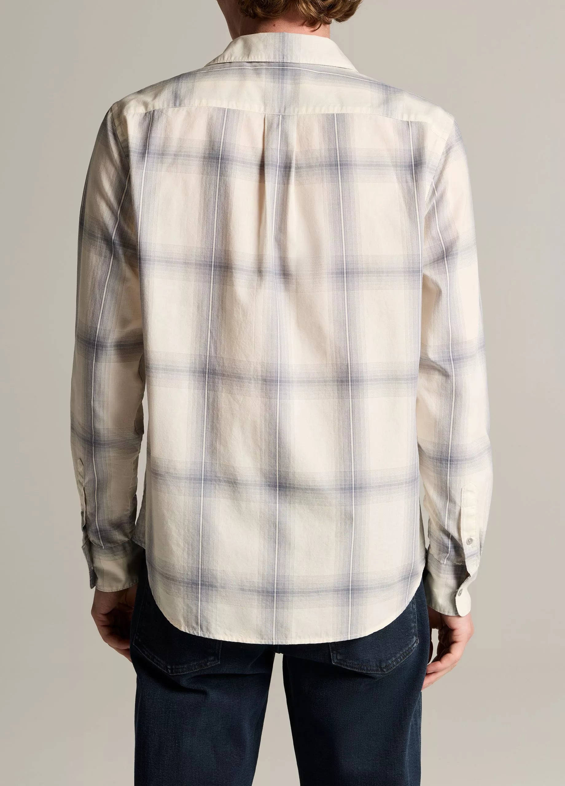 A person is seen from the back, standing against a neutral background and wearing the Vince Townes Plaid Long Sleeve Shirt in a cream and light blue shadow plaid, paired with dark pants.
