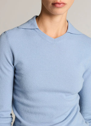 A person wearing the Vince Long Sleeve High V-Neck Polo Sweater in light blue, shown from shoulders to mid-torso against a neutral background.