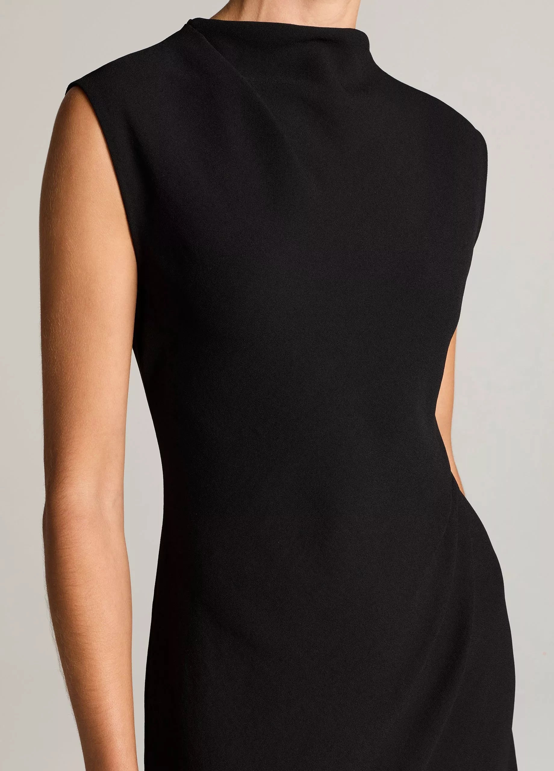 A model wears the vince Draped Funnel Neck Dress—a sleeveless black design with a high neckline—shown from the shoulders to mid-thigh against a neutral background.