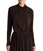 A person is shown from the shoulders to just above the knees, wearing the Vince Long Sleeve Draped Cowl Blouse and a matching dark brown skirt in matte jersey, photographed against a white background.