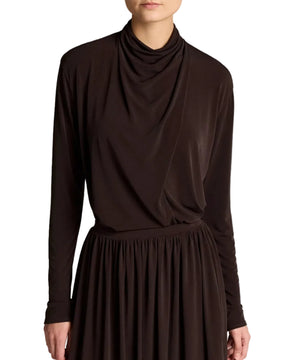 A person is shown from the shoulders to just above the knees, wearing the Vince Long Sleeve Draped Cowl Blouse and a matching dark brown skirt in matte jersey, photographed against a white background.