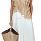 A person wears the Proenza Schouler Ezra Dress—a beige and white drawstring-waist style with a cinched silhouette—while holding a large beige tote bag.