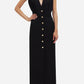 Woman wearing the Luna Friesian Long Dress by Blaze Milano—sleeveless, black, long, with a deep V-neck and gold-tone buttons, standing with one hand on her hip.