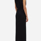 A woman faces away, wearing the Luna Friesian Long Dress by Blaze Milano—sleeveless, black with gold-tone buttons—and black heels against a white background.