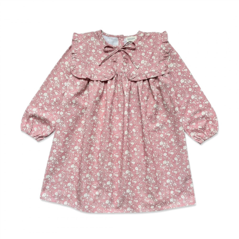 The Girls’ Celicia Dress by Louis Louise is a long-sleeved pink floral dress featuring a ruffled square bib collar, front bow detail, gathered cuffs, and a flattering flared fit.