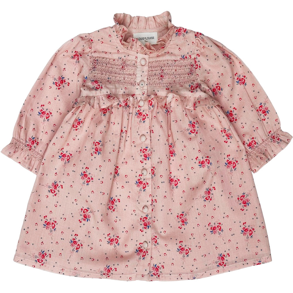 The Louis Louise Baby Girls' Coralie Cotton Veil Romantic Flower Dress is a long-sleeved pink floral dress with a smocked chest, button-down front, and ruffled high collar.