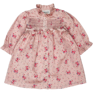 The Louis Louise Baby Girls' Coralie Cotton Veil Romantic Flower Dress is a long-sleeved pink floral dress with a smocked chest, button-down front, and ruffled high collar.