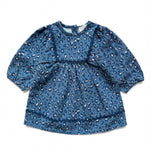 The Baby Girls’ Maha Dress by Louis Louise is a blue, long-sleeve toddler denim dress featuring an all-over leopard print and a gathered flared waist, displayed laid flat on a white background.