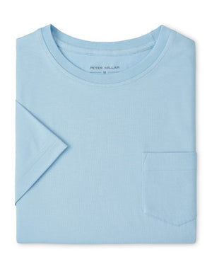 The Peter Millar Crown Comfort Pocket Tee, a light blue short-sleeve shirt crafted from soft organic cotton with a chest pocket, is neatly folded and displayed on a plain white background.