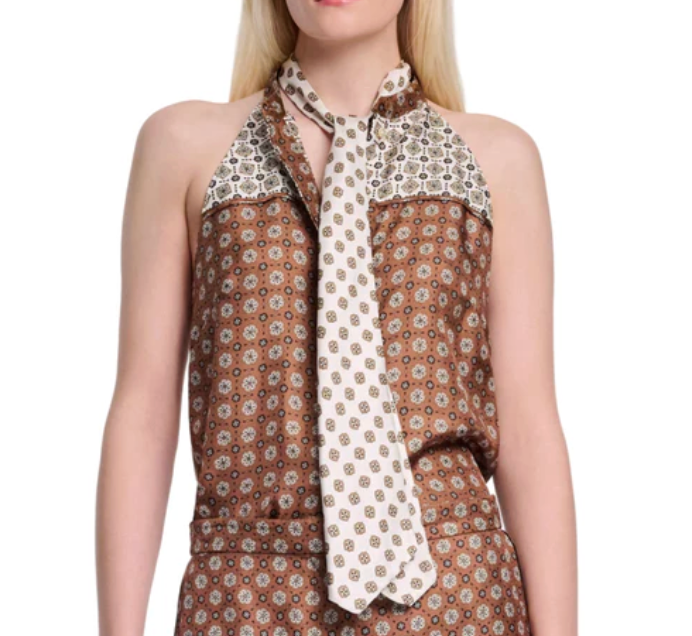 A woman wears Dorothee Schumacher's Graphic Dreams Top, a sleeveless patterned brown piece with matching pants and a contrasting white necktie, showcasing the brand’s signature prints.