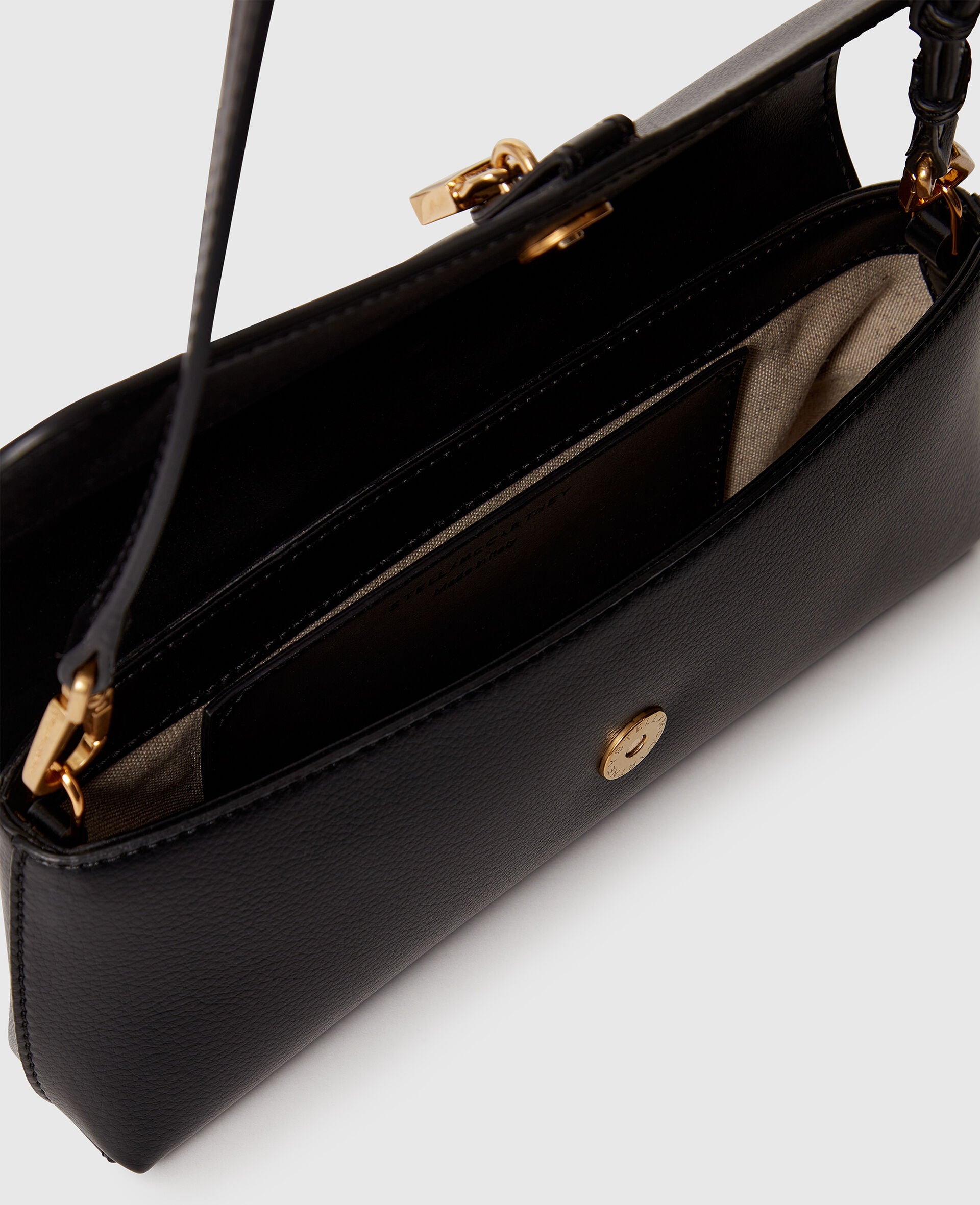 The Ryder Pouchette Shoulder Bag by Stella McCartney features cruelty-free black leather, a gold clasp, and a beige-lined interior with pockets and a zip compartment.