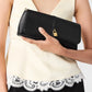 A person in a cream lace-trim top holds the Stella McCartney Ryder Pouchette Shoulder Bag, a vegan black clutch with a gold padlock detail.