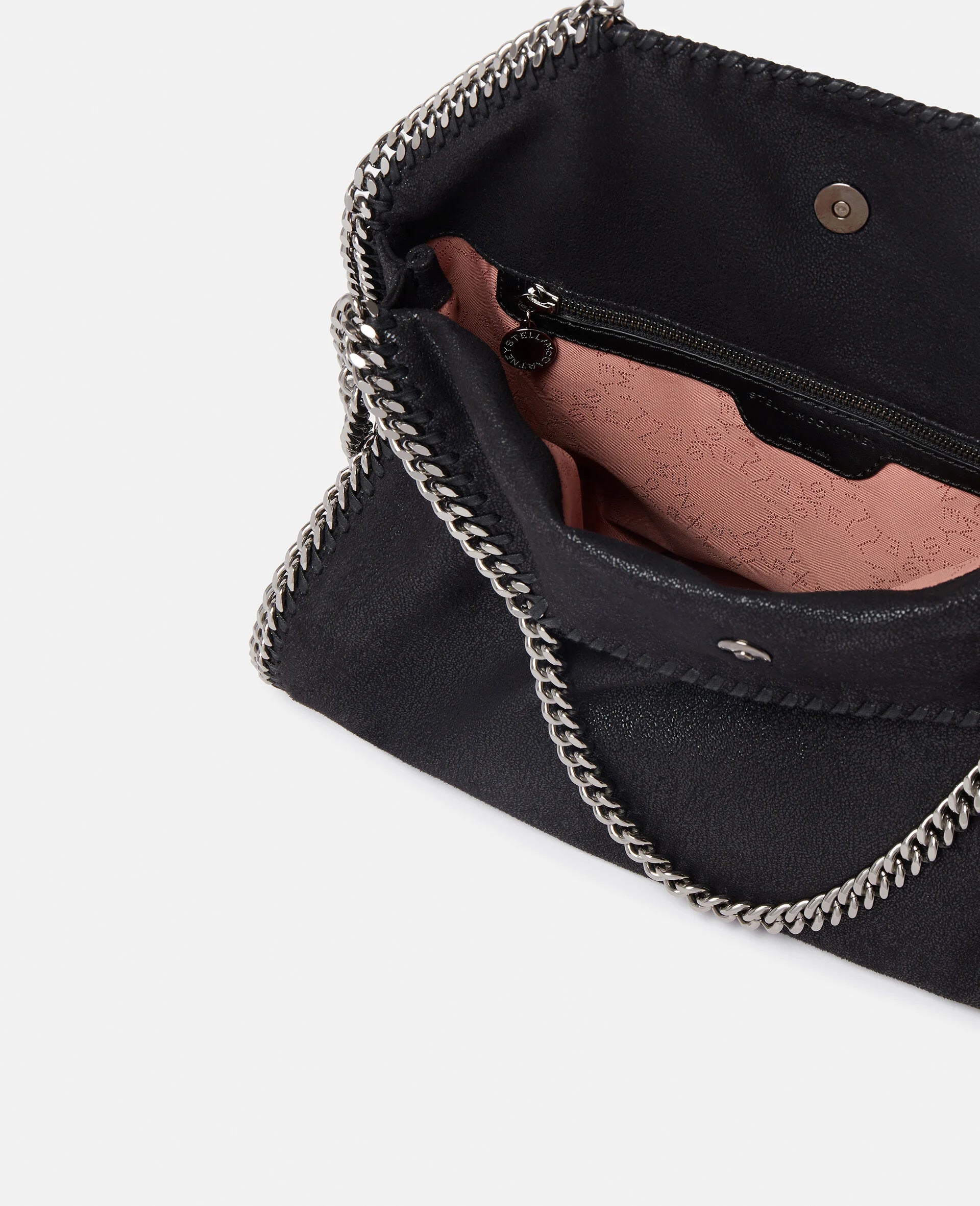 The Stella McCartney Falabella Fold Over Tote features a black exterior with silver chain trim, a light pink lining, and a zippered pocket; this stylish vegan bag is crafted from recycled plastic bottles.
