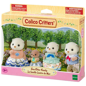 The Calico Critters Sea Otter Family toy set includes four plush otter figures dressed in charming fabric outfits with a subtle shell motif, attractively displayed outdoors on the packaging.