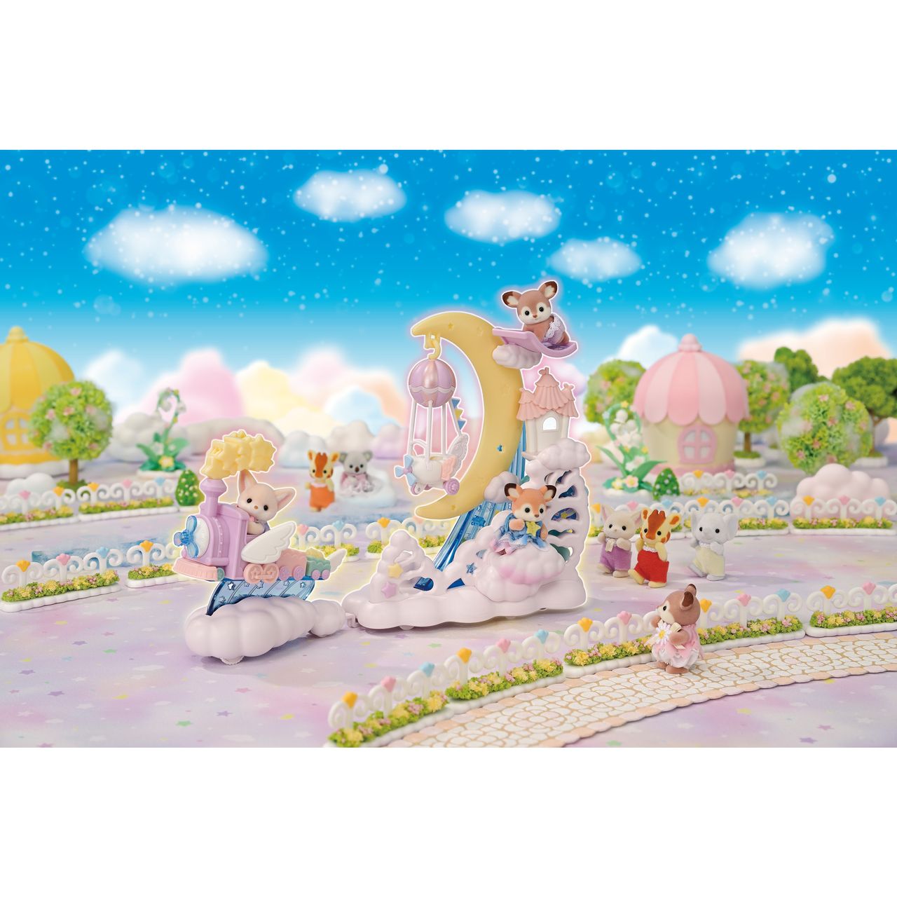 Calico Critters Daydream Parade Playset features miniature animal figurines in a pastel, fantasy-themed park adorned with a crescent moon structure, fluffy clouds, and a starry sky backdrop. Some figurines are sitting, reading, or climbing, while others gather near the whimsical moon float that glides gently across the scene.