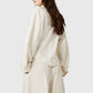 A person with long brown hair, seen from behind against a plain background, wears Stella McCartney’s oversized Washed Cotton Utility Top in cream with matching loose pants.