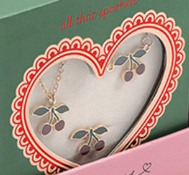 Konges Slojd Jewelery Set features cherry-shaped necklace and earrings with gold outlines, green leaves, and red cherries in a heart-shaped box window.