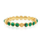 The Berry Gem Hinged Bangle by Juliska Capucine De Wulf showcases alternating round green gem-drops and textured gold beads, elegantly displayed on a white background.
