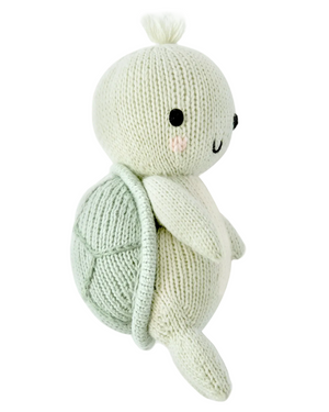The Kelp Green Sea Turtle - Baby 7" from Cuddle + Kind is a hand-knit plush turtle made from heirloom-quality Peruvian cotton yarn, featuring a light green shell, cream-colored body, black stitched eyes, and a small tuft of yarn on its head for lasting softness and charm.