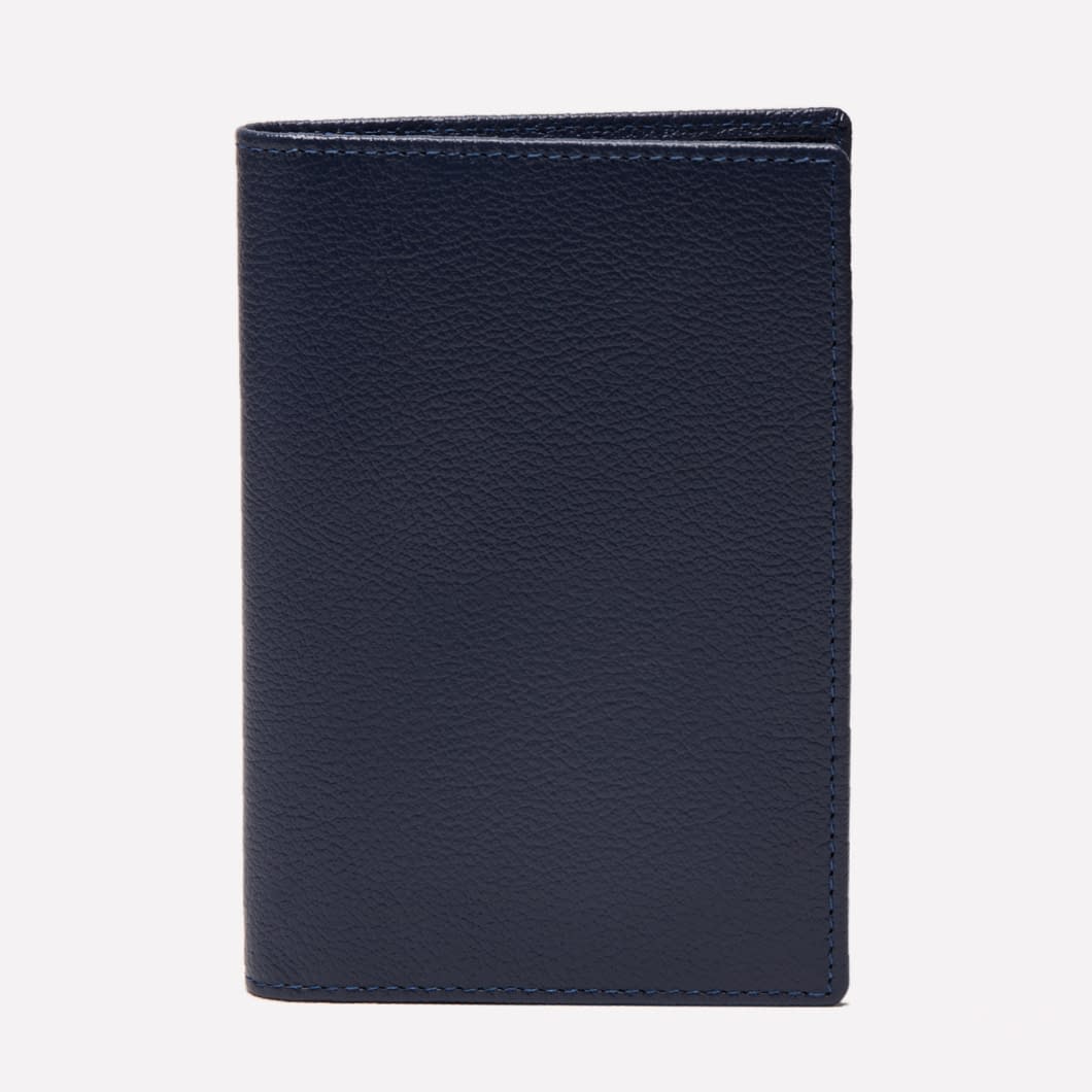 An upright Ettinger Capra Passport Case in closed, dark blue Capra leather is displayed against a plain white background.