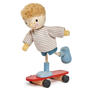 Edward & His Skateboard by Tender Leaf Toys features Edward, a solid wood figure with blond hair, a striped shirt, and blue shoes, balancing on one leg atop his red skateboard.