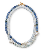 The Lizzie Fortunato Cabana Necklace highlights a double-stranded design adorned with semiprecious beads in shades of blue, white, and green. It includes three large white pearls and is gracefully fastened with a gold clasp.