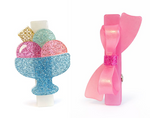 Add a playful pop to your look with the Lillies & Roses Ice Cream Sunday & Bow Hair Clips—one clip features a glittery ice cream sundae design, while the other sports a charming pink bow with a sparkling center. Handcrafted for extra flair, these cute summer hair clips are beautifully displayed on white backgrounds.