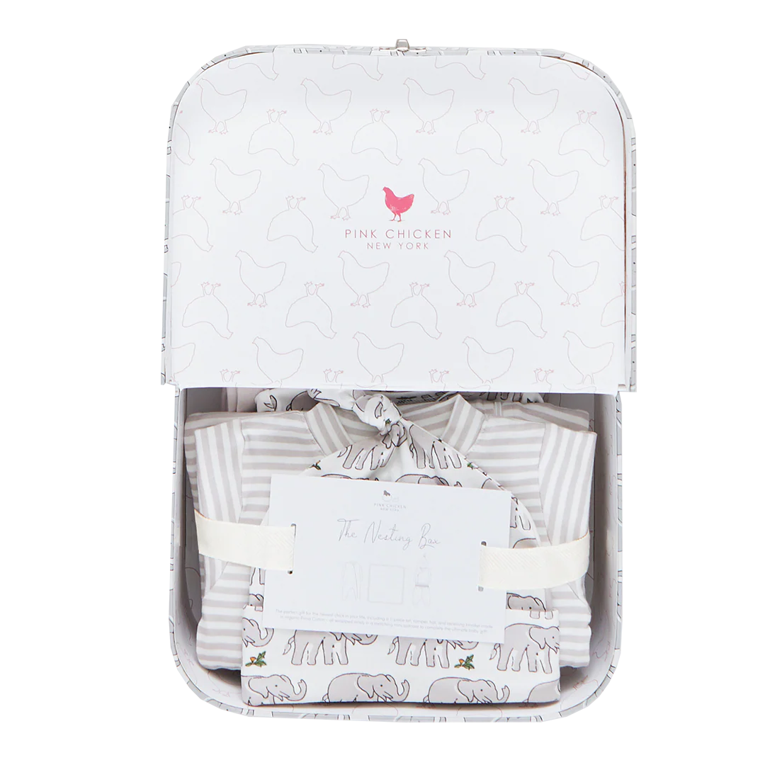 The Pink Chicken Nesting Box Baby Take Home Set features folded striped and animal-print organic pima cotton baby clothing, presented in a gift box with ribbon and card—perfect for newborns.