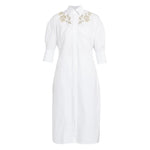 The Crystal Flower Embellished Shirt Dress by Erdem is a white cotton poplin, knee-length dress with three-quarter sleeves, floral crystal detailing on the shoulders, and a stylish tie-fastening belt.
