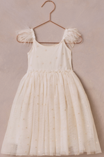 The Girls' Poppy Dress by Noralee is cream-colored, sleeveless, and features a tulle skirt with floral embroidery and sheer ruffled straps, shown on a rose gold hanger against a light beige background.