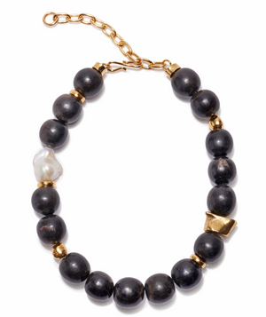 The Oria Necklace by Lizzie Fortunato features large black horn beads, small gold spacers, an irregular freshwater pearl, and a gold adjustable chain clasp.