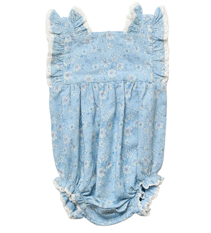Introducing the Early Sunday Baby Girls’ Eva Baby Romper—a light blue romper adorned with a charming white floral pattern, featuring ruffled shoulder straps, delicate white lace trim, and elastic leg openings. This darling piece offers stylish comfort in every detail for your little one.