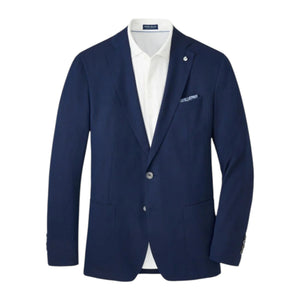 The Excursionist Flex Blazer by Peter Millar features a navy blue wool-silk blend with notch lapels, two front buttons, patch pockets, and a white dress shirt underneath. A pocket square peeks from the chest pocket.
